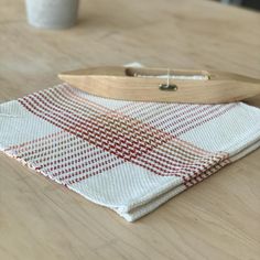 a wooden paddle sitting on top of a white and red checkered table cloth next to a cup