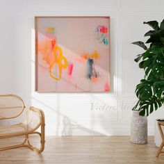 an abstract painting hangs on the wall next to a chair and potted plant in a white room