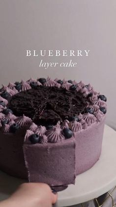 a person cutting into a blueberry layer cake