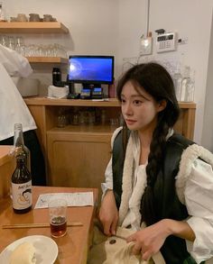 a woman sitting at a table with food and drinks