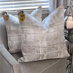 two pillows sitting on top of a couch next to a table with a candle in it