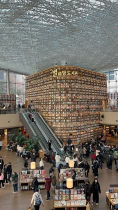 people are walking around in an open area with many books on the walls and stairs