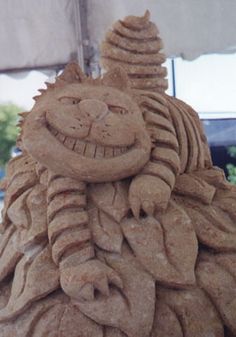 a sand sculpture with a cat on it's head and eyes, sitting under an umbrella