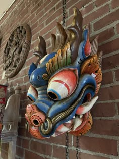 a dragon head hanging from the side of a brick wall next to two other masks