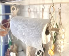 a close up of a toilet paper roll hanging from a hook on a wall with other items in the background