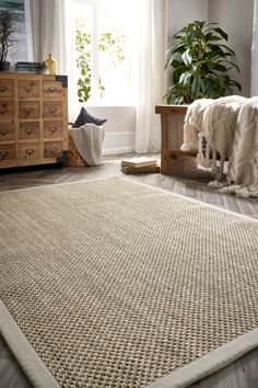 a large rug in the middle of a living room with wooden furniture and potted plants