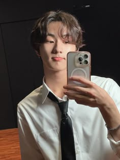 a man taking a selfie with his cell phone in front of him and wearing a neck tie