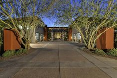 an entrance to a building with trees in the front and walkway leading up to it