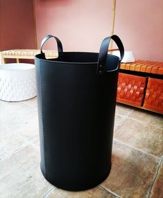 a large black bucket sitting on top of a tiled floor