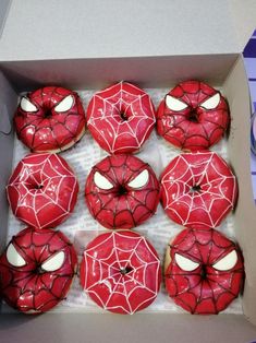 a box filled with red donuts covered in spiderman's webs and white frosting