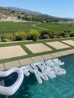 an inflatable pool float with the word love spelled out on it next to a swimming pool