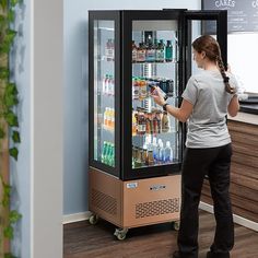 a woman standing in front of a vending machine with drinks on the doors and shelves