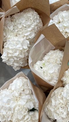 white flowers are in brown paper bags on the table