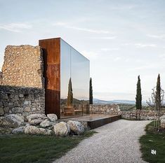 a large mirror sitting on the side of a stone wall next to a gravel road