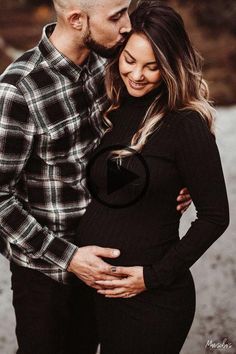 a pregnant couple cuddles and smiles at the camera