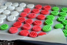 there are many different colored cookies on the tray together, and one is white with green in the middle