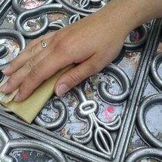 a person with their hand on top of a piece of paper next to a metal grate