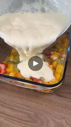 someone pouring dressing into a glass container filled with fruit