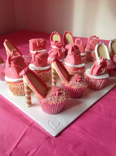 a table topped with lots of cupcakes covered in pink frosting and bows