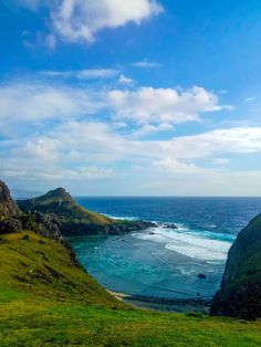 an ocean view from the top of a hill with green grass and blue water in the foreground