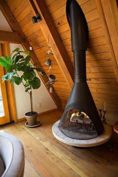 a wood burning stove in the corner of a room with wooden walls and ceiling beams