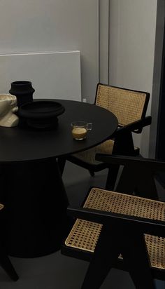 a black table with two chairs next to it and a vase sitting on top of the table