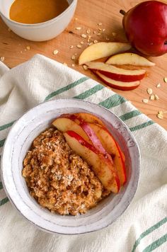 a bowl of oatmeal with apples and an apple on the side