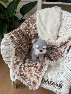 a teddy bear is sitting on a chair with a blanket over it's head