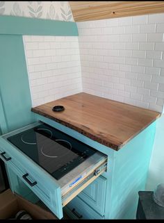 a stove top oven sitting inside of a kitchen next to a wooden counter and white tiled walls