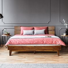 a bed sitting on top of a wooden floor next to two tables