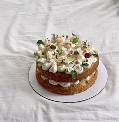 a cake with white frosting and toppings on a plate sitting on a bed