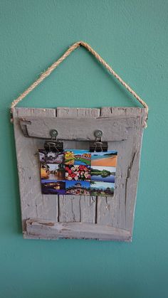 an old wooden frame hanging on a wall with pictures hung to it's sides