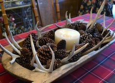 a candle and antlers in a wooden bowl on a table