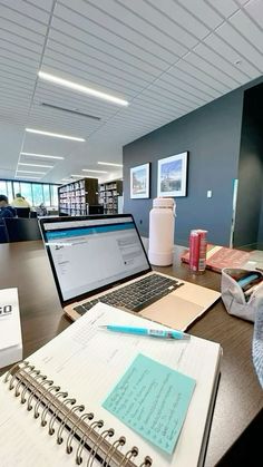 an open laptop computer sitting on top of a desk next to a note pad and pen