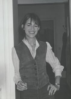 a black and white photo of a woman standing in front of a door with her hands on her hips