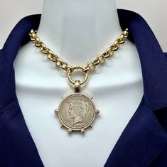 a gold chain with a coin on it is attached to a mannequin head