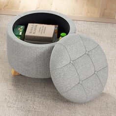 a grey ottoman with books in it on the floor