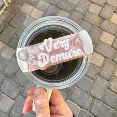 a person holding up a plastic cup with the word merry demure on it