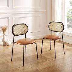 two chairs sitting next to each other on top of a hard wood floor in front of a window