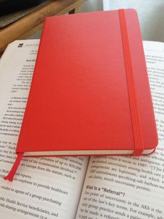 a red notebook sitting on top of an open book