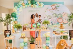 a couple and their children are standing in front of an animal themed birthday cake table