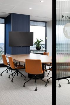 a conference room with chairs and a flat screen tv mounted to the wall in front of a panoramic window