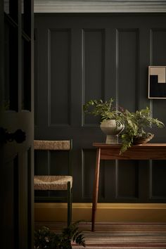 a wooden table sitting next to a plant on top of a rug in a room