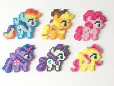 pixelated pony broochies are arranged on a white surface, including pink, purple, yellow and orange