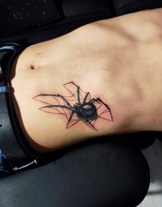 a black spider tattoo on the side of a woman's lower back ribcage