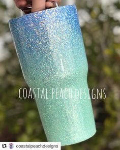 a hand holding a blue and green glittered cup with the words coastal peach designs on it