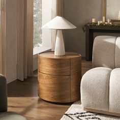 a white lamp sitting on top of a wooden table next to a couch in a living room