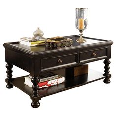 a coffee table with two drawers and a candle on the top, surrounded by books