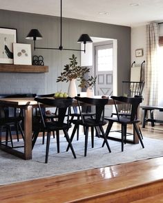 a dining room table with chairs and a vase on it's centerpiece in front of a fireplace