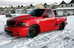 a red pick up truck parked in the snow